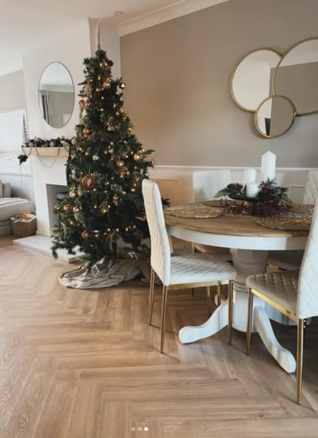 light modern living room and dining space, round wood & white dining table with tall back cream velvet chairs with gold legs, christmas tree behind