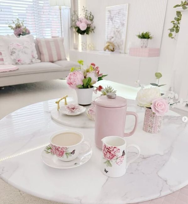 round white marble coffee table styled with pink floral china ware in birght living room